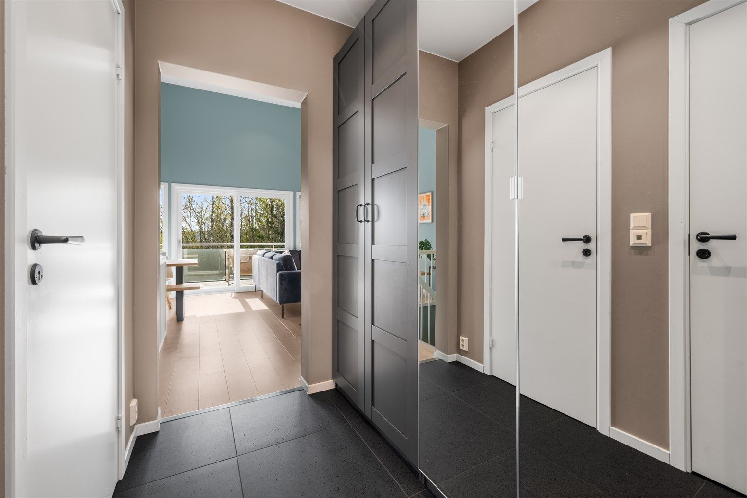 Fra gangen åpner boligen seg opp mot stuen og kjøkkenet, med et gjennomgående lyst parkettgulv som binder rommene sammen.