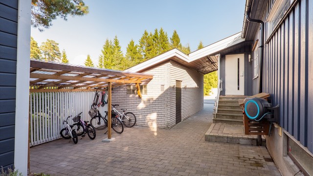Foran inngangspartiet er sykkelparkering med skjermende overbygg anlagt. Ytterdøren ble skiftet ut samtidig med vinduer i 2015.
