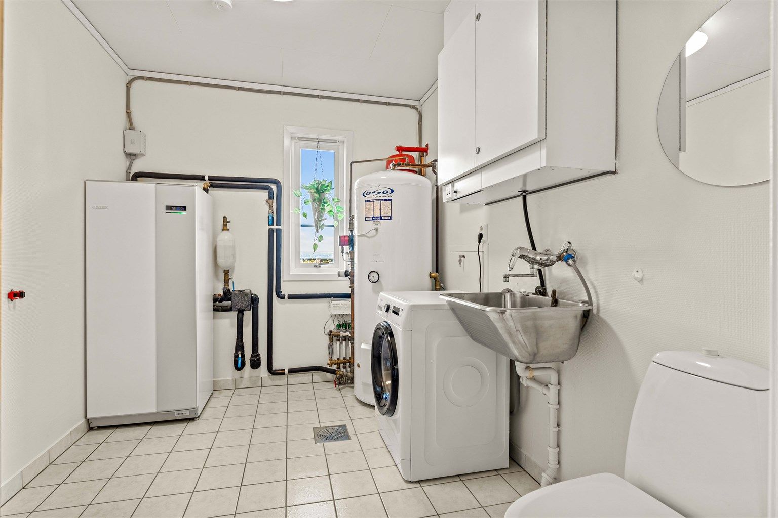 Separat vaskerom med flislagt gulv med varme. Her er boligens tekniske anlegg samlet, inkludert varmtvannsbereder og aggregat for balansert ventilasjon.