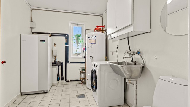 Separat vaskerom med flislagt gulv med varme. Her er boligens tekniske anlegg samlet, inkludert varmtvannsbereder og aggregat for balansert ventilasjon.