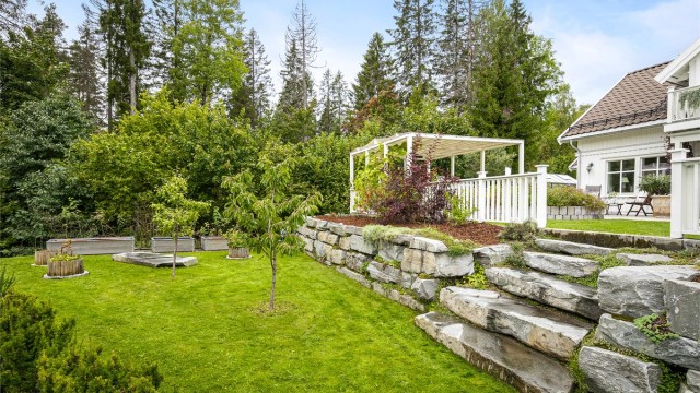 Tomten er opparbeidet i nivåer med solide forstøtningsmurer og trapper i naturstein.