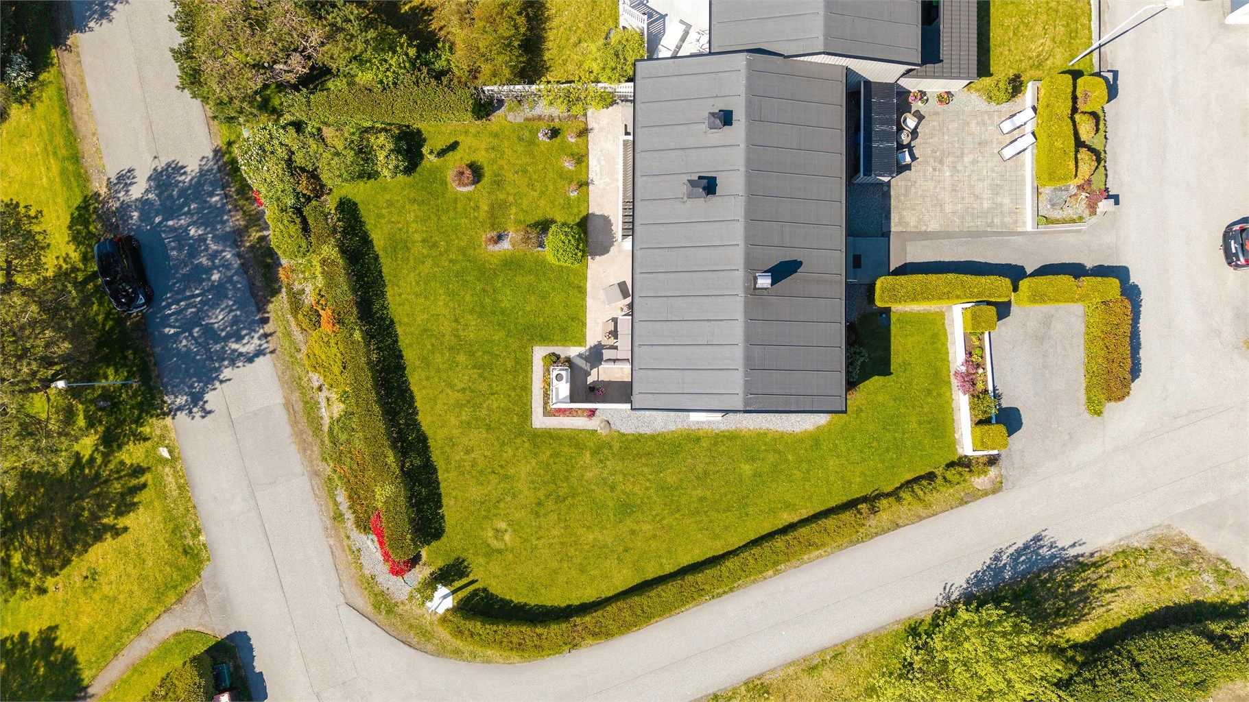 Tomten er opparbeidet med plen, hekk, asfalt og støpte platter