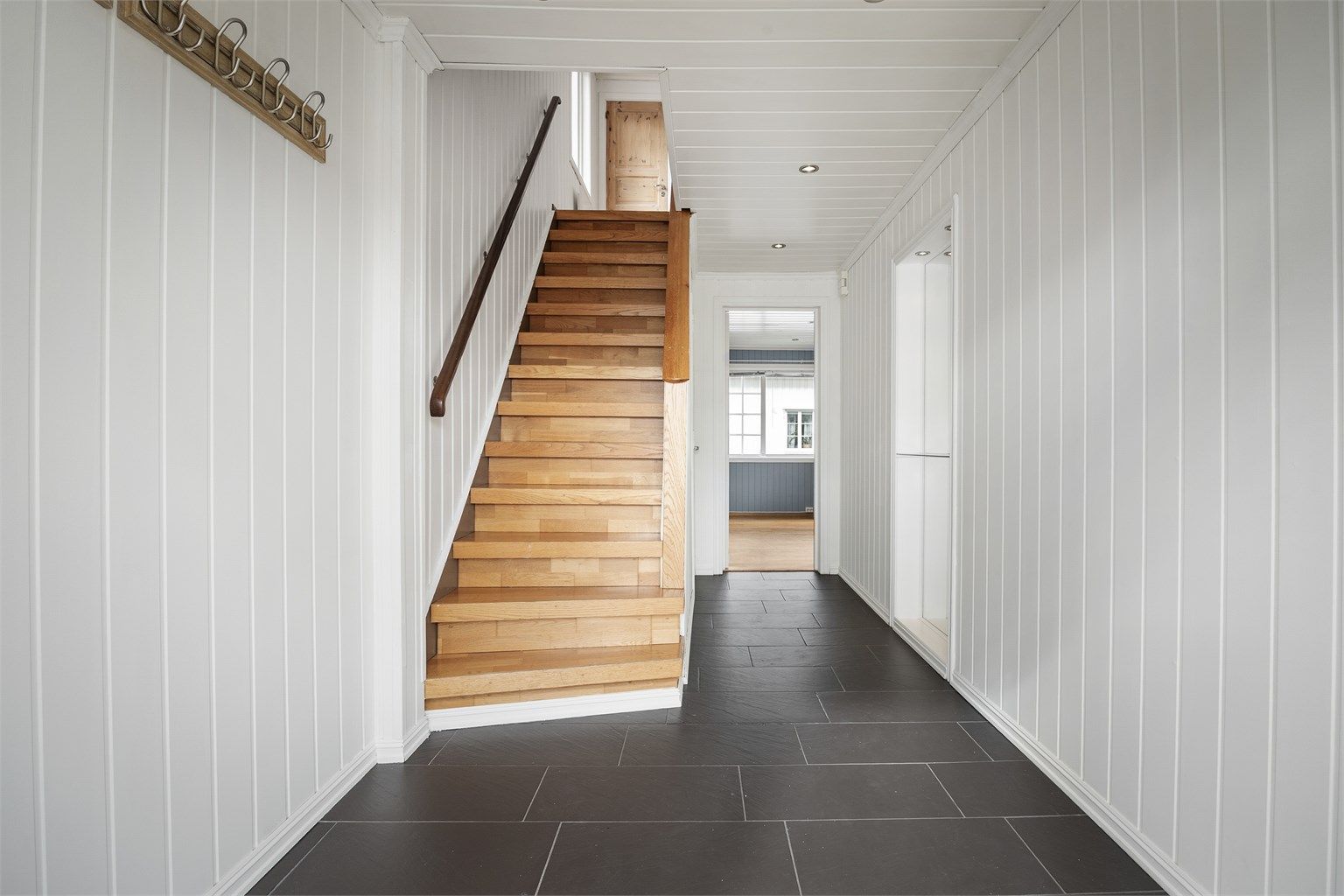 Entré med fliser på gulv og paneler på vegg og himling