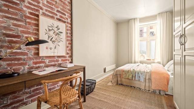 Et personlig soverom med en vakker original teglsteinsvegg og egen plass til hjemmekontor.