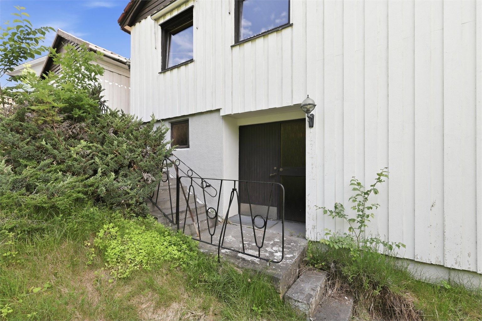 Utvendig betongtrapp leder ned til den separate inngangen i underetasjen.
