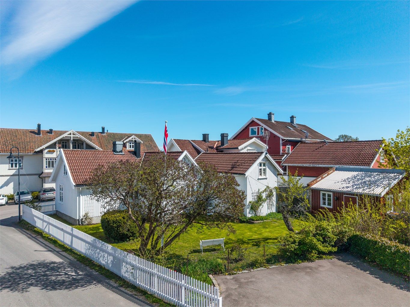 Denne sjarmerende eneboligen fra midten av 1700-tallet er rammet inn av et hvitt stakittgjerde. Innenfor ligger en idyllisk hage med bla. flaggstang og bryggerhus.
Foto: Fotofinish AS v/Kristian Bollæren