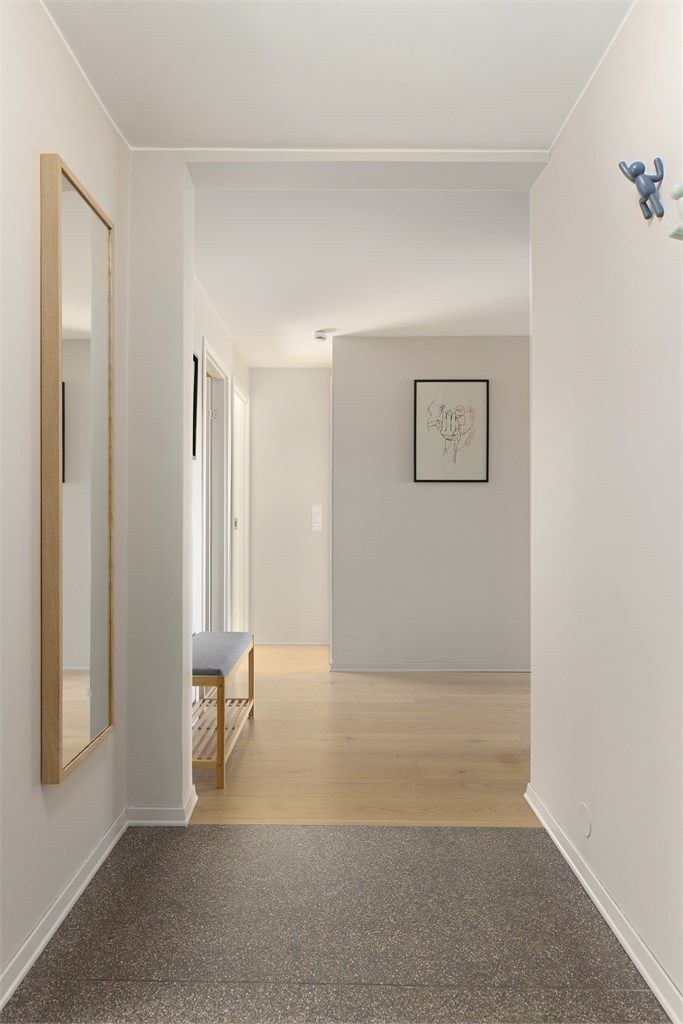 Entréen har flislagt gulv med behagelig gulvvarme og slette malte vegger som er listefrie mot himlingen - en moderne detalj som går igjen i resten av boligen.