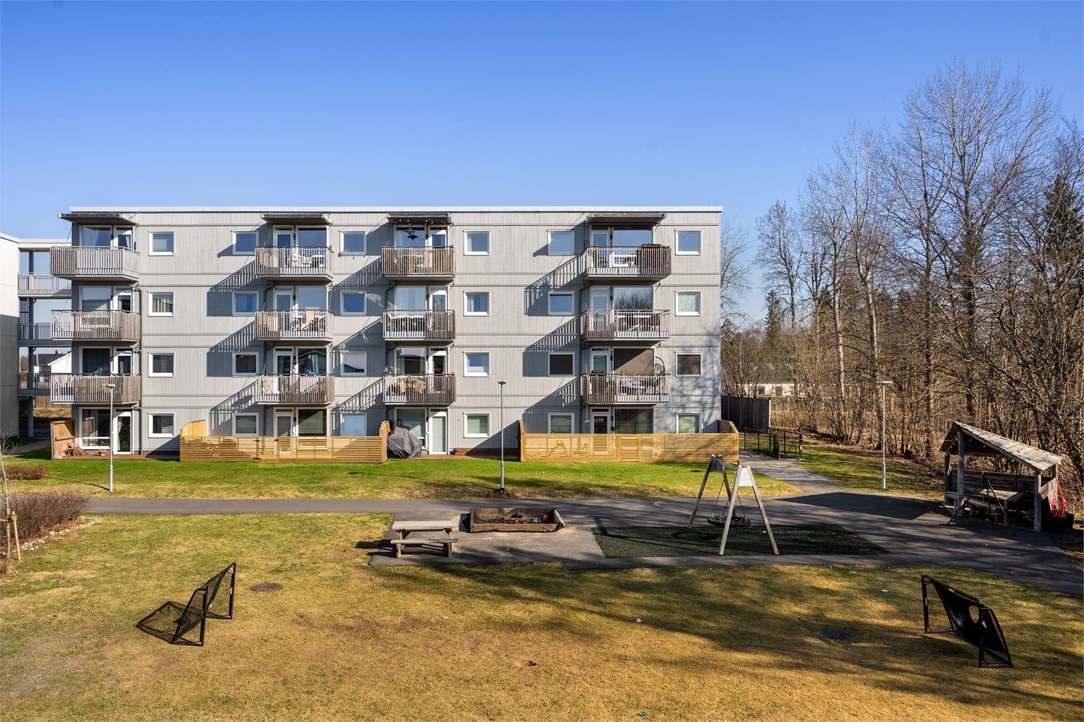 Tomten opparbeidet med asfalterte internveier, sittebenker, lekeapparater, plenarealer, prydbusker og diverse beplantning.