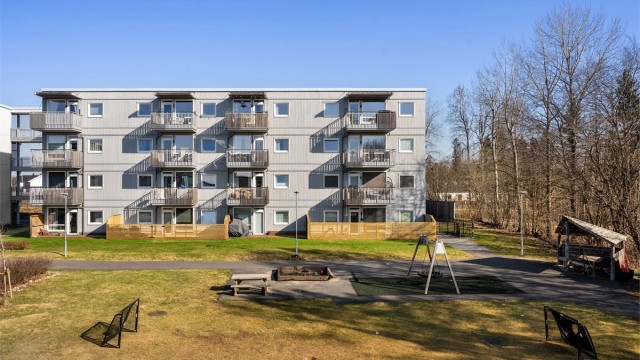 Tomten opparbeidet med asfalterte internveier, sittebenker, lekeapparater, plenarealer, prydbusker og diverse beplantning.