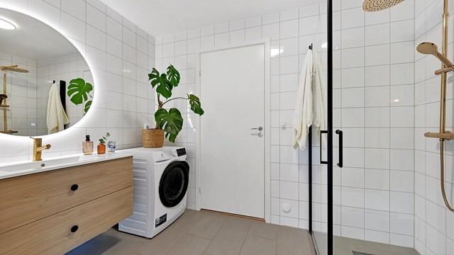 Delikat flislagt bad med elektriske varmekabler, opplegg for vaskemaskin og vegghengt toalett.