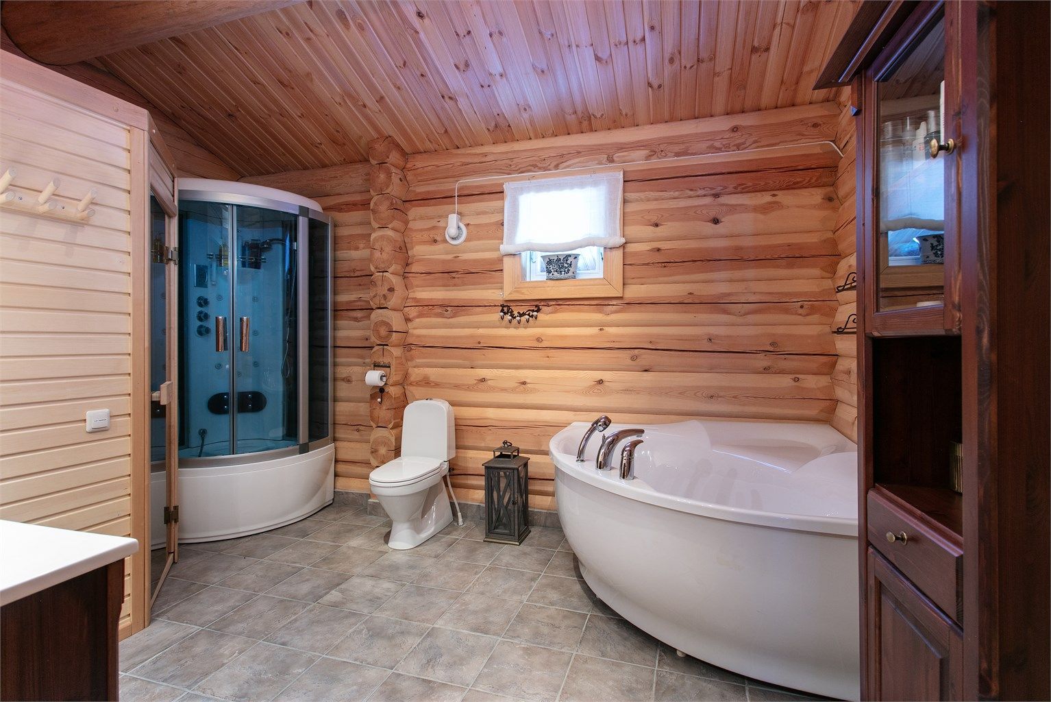 Romsmlig bad med flislagt med elektriske varmekabler, vegger i panel/tømmer og panel i tak