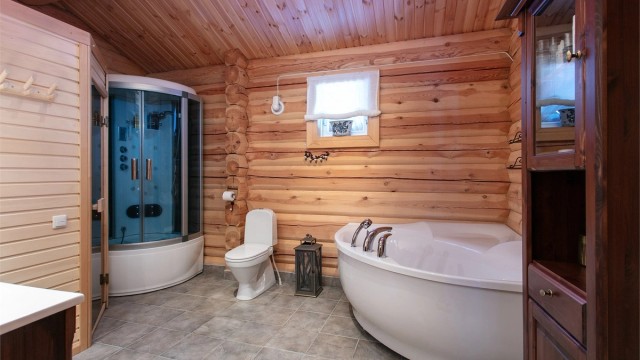 Romsmlig bad med flislagt med elektriske varmekabler, vegger i panel/tømmer og panel i tak