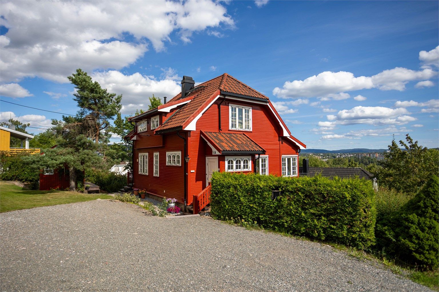 Huset ligger høyt og fritt med utsikt over området. Eiendommen har en stor, gruset gårdsplass med ladestasjon for elbil.