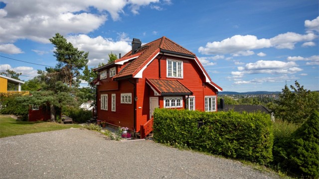 Huset ligger høyt og fritt med utsikt over området. Eiendommen har en stor, gruset gårdsplass med ladestasjon for elbil.