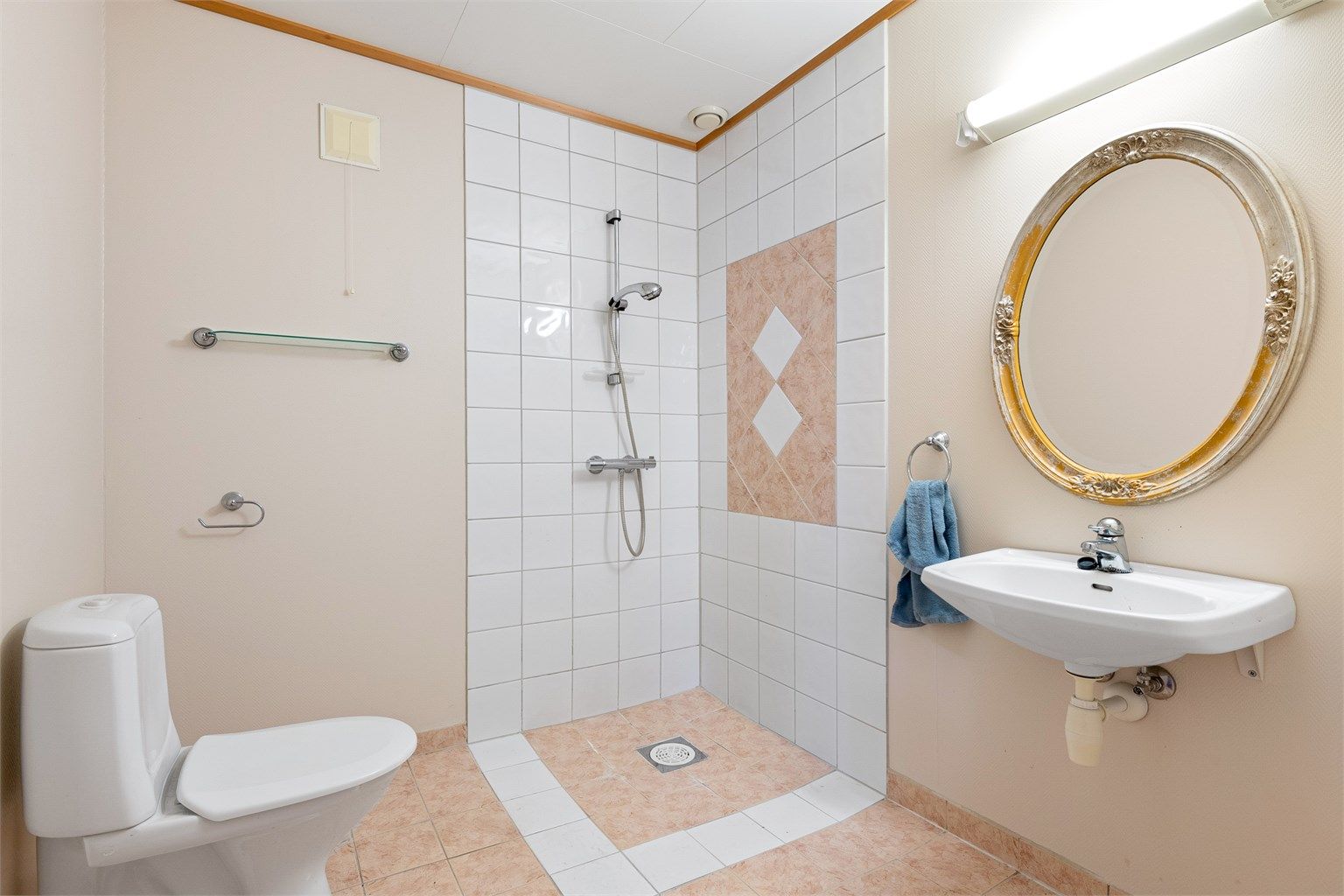 Flislagt bad i underetasjen, Dusjhjørne med vegghengt dusjarmatur. Servant og toalett.