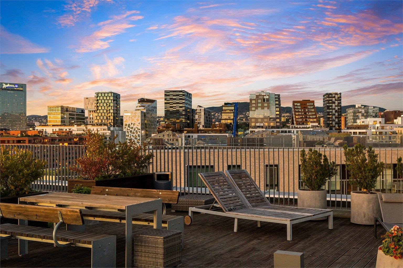 Utsikt fra takterrasse mot Barcode og Oslos skyline i kveldslys