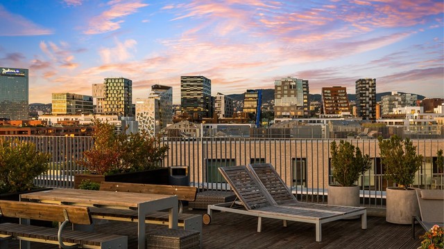 Utsikt fra takterrasse mot Barcode og Oslos skyline i kveldslys