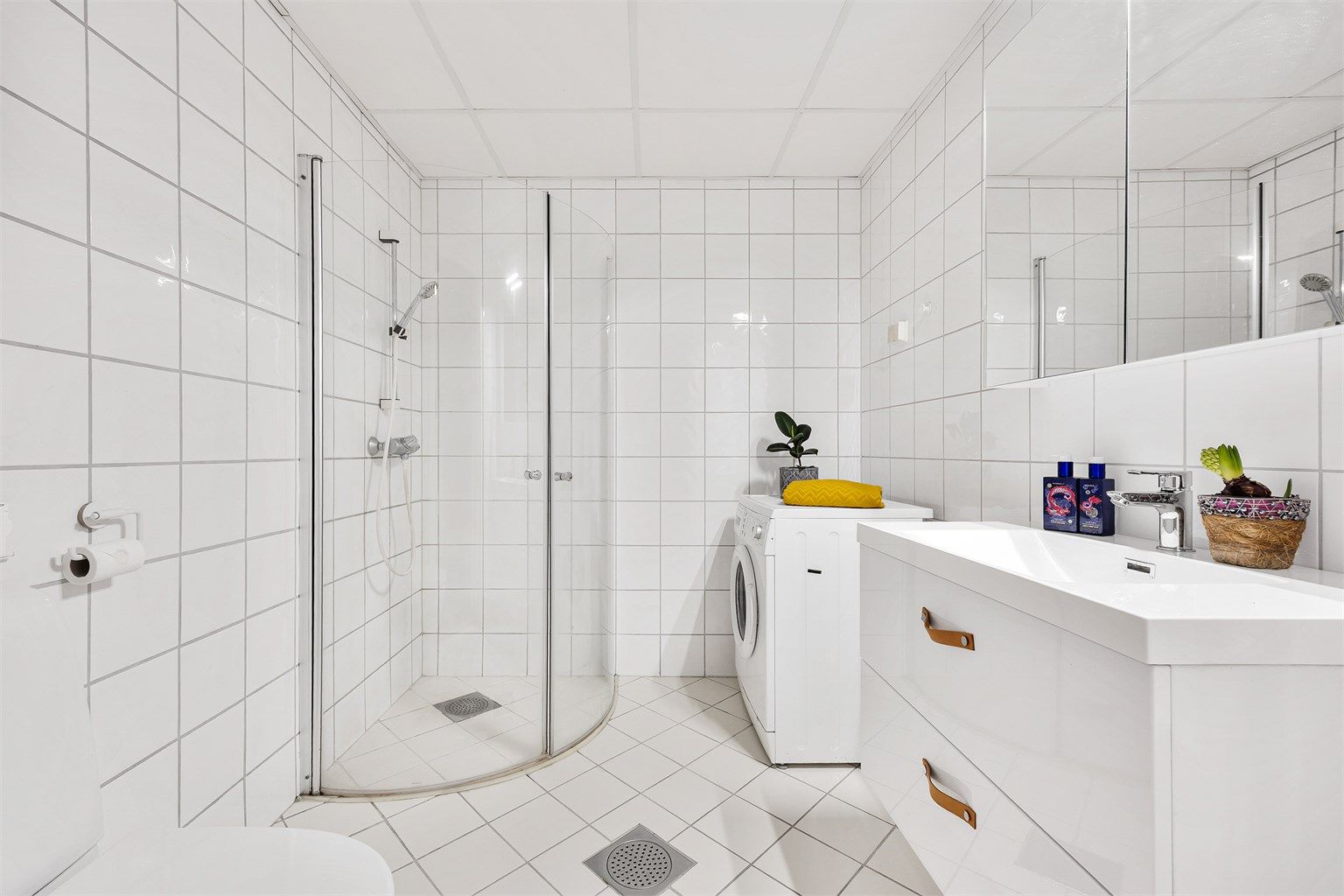 Rommet er helfliset og utstyrt med dusjhjørne med innfellbare glassdører, samt opplegg for vaskemaskin.