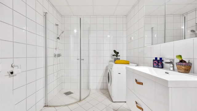 Rommet er helfliset og utstyrt med dusjhjørne med innfellbare glassdører, samt opplegg for vaskemaskin.