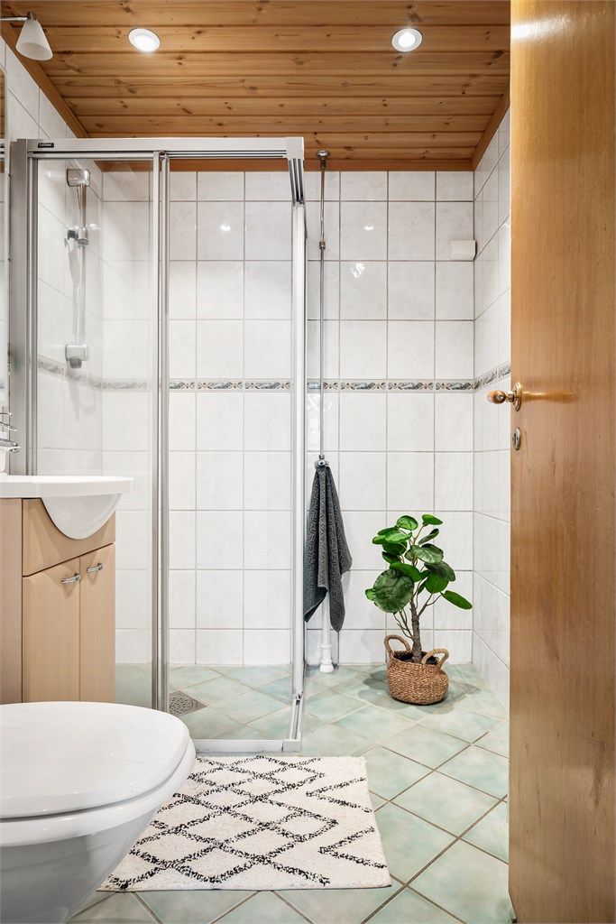 Badet har dusjhjørne med skyvedørsramme og gulvstående toalett.