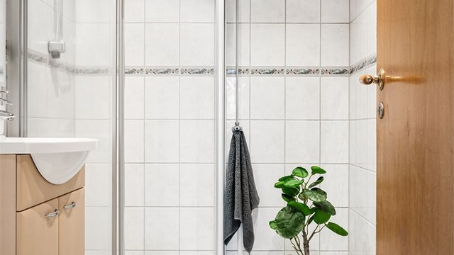Badet har dusjhjørne med skyvedørsramme og gulvstående toalett.