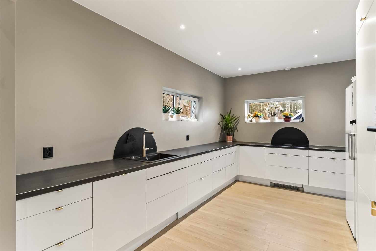 Kjøkken i hovedetasjen har delvis åpen løsning mot den romslige stuen. Kjøkkeninnredningen ble montert i 2023 og har slette, moderne fronter og benkeplater av laminat. Her får du rikelig med skap- og benkeplass. 