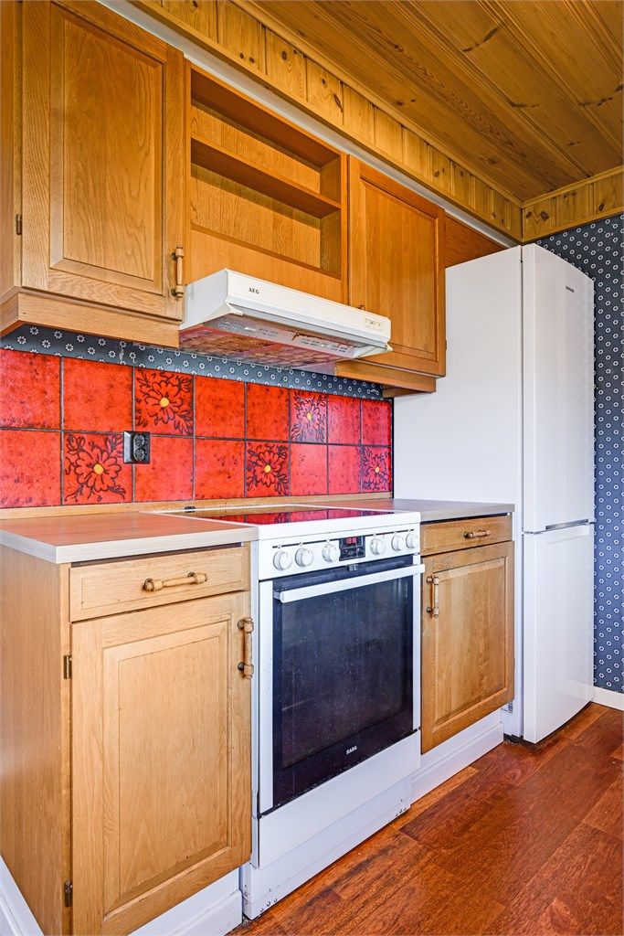 Kjøkkenet er utstyrt med komfyr, kjøleskap og kjøkkenventilator med avtrekk ut.