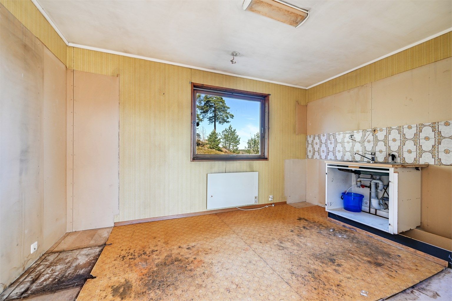Rommet er et separat kjøkken i hovedetasjen, med utsikt mot naturen bak huset.