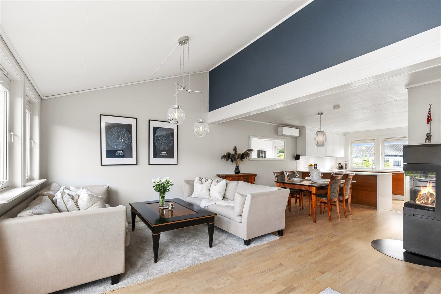 Romslig og lys stue med store vindusflater og stor takhøyde som gir en luftig atmosfære. 