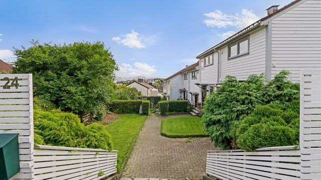 Inngang fra gateplan med steinlagt gangsti til rekkehuset.