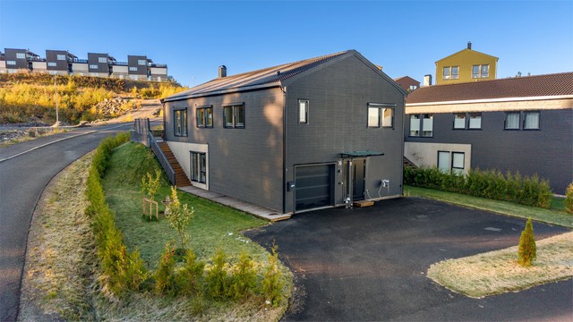 Boligen har integrert garasje i underetasjen og utvendig trappeadkomst til hagen.