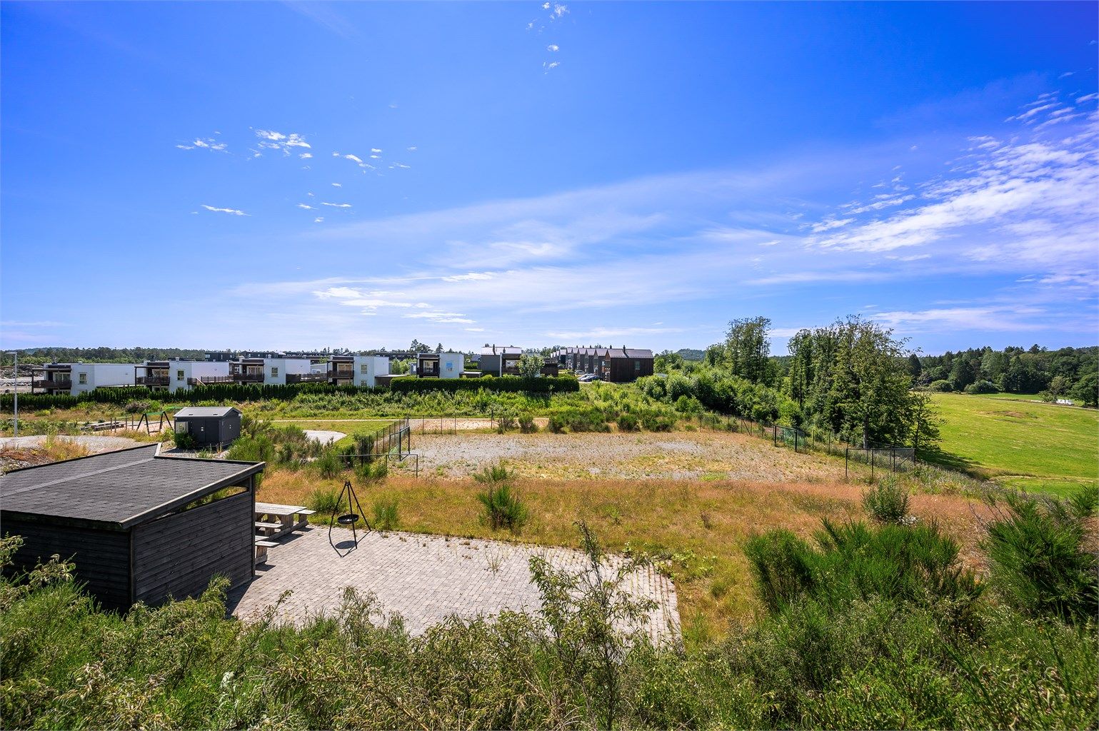 Felles friområde like ved med balløkke, lekeplass og sitteplass i landlige omgivelser.