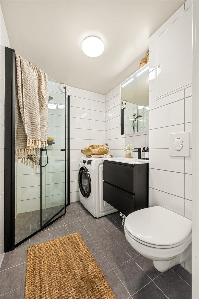 Badet er innredet med vegghengt klosett, servantmøbel og dusjhjørne med svingbare glassdører.