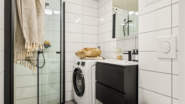 Badet er innredet med vegghengt klosett, servantmøbel og dusjhjørne med svingbare glassdører.