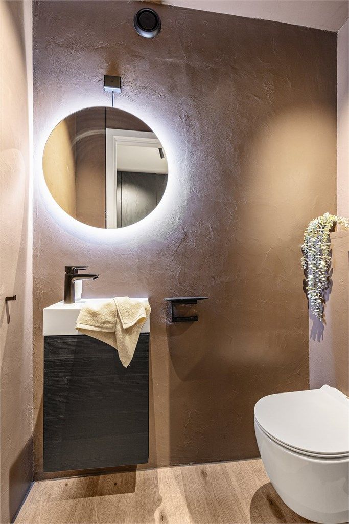 Leiligheten har et separat toalettrom, også fornyet i 2023 med mikrosement, og består av servant, speil og vegghengt toalett.