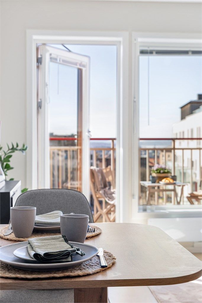 Balkongdøren, med karm av tre, åpner opp og visker ut skillet mellom inne og ute.