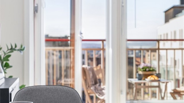 Balkongdøren, med karm av tre, åpner opp og visker ut skillet mellom inne og ute.