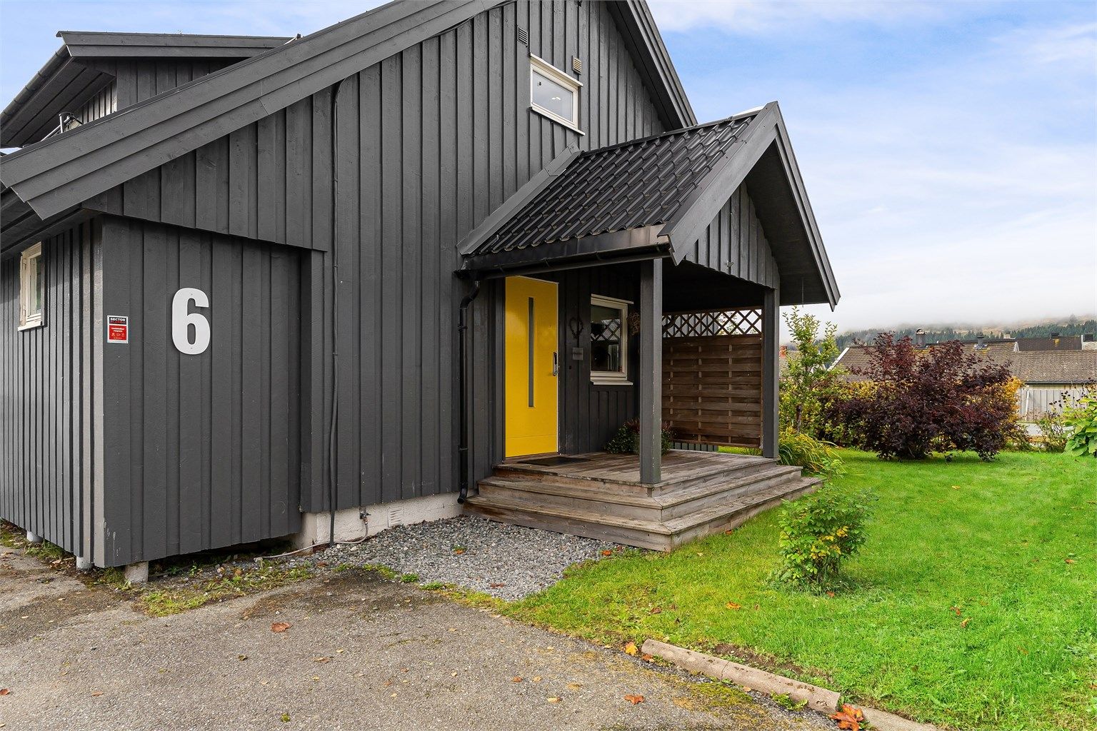 Overbygd inngangsparti med trapp i tre og ytterdør fra 2019.