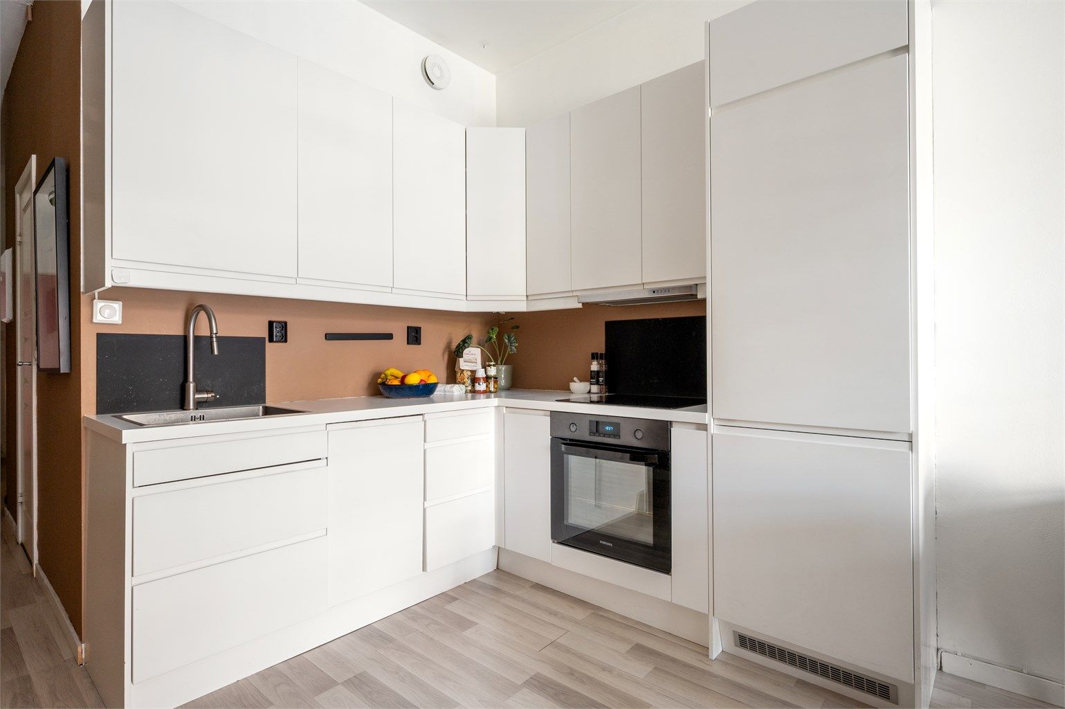 Kjøkkenet er utstyrt med glatte fronter, benkeplate av laminat, nedfelt oppvaskkum i tillegg til kjøleskap med fryser og integrert oppvaskmaskin, stekeovn og induksjonstopp.