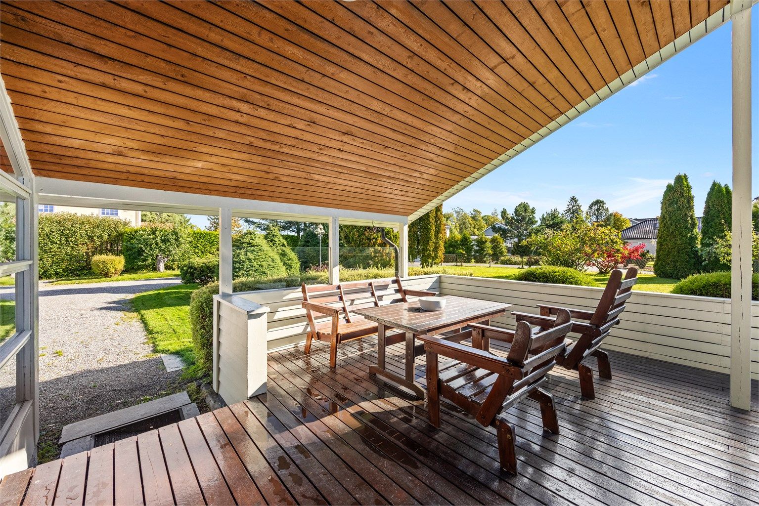 Overbygd terrasse med god plass til sittegruppe og utsyn mot hagen.