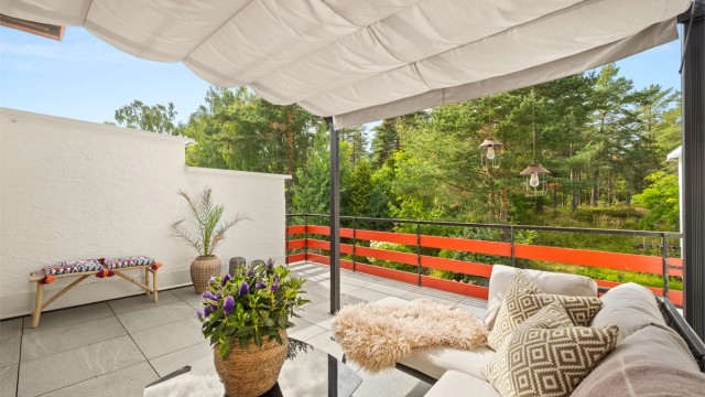 Altanen er belagt med store heller, og en frittstående pergola med uttrekkbar duk gir mulighet for skjerming over deler av sitteplassen.