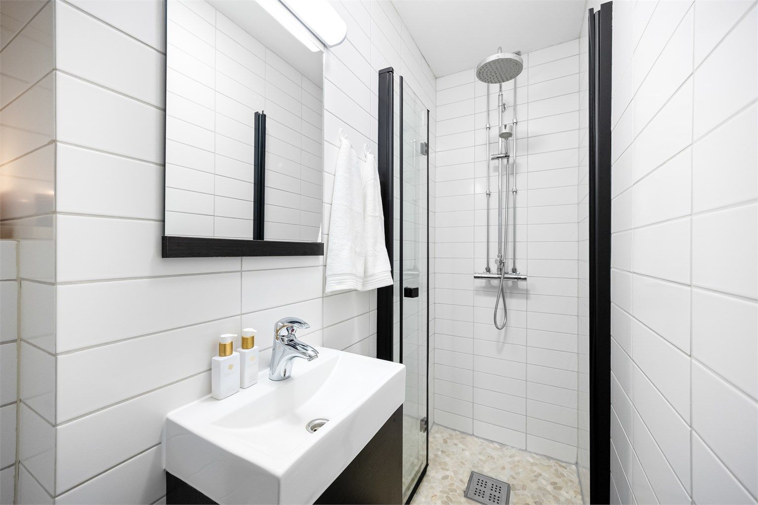 Badet er innredet med vegghengt servantskap med ovenpåliggende vask og speil med belysning.