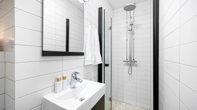 Badet er innredet med vegghengt servantskap med ovenpåliggende vask og speil med belysning.