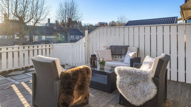 Terrassen har en veggmontert markise for solskjerming.