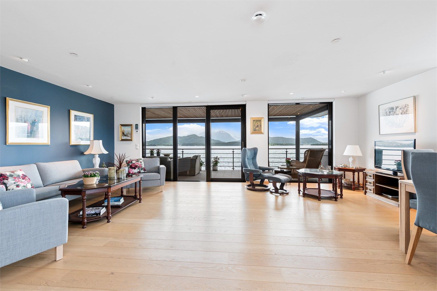 Romslig stue med lyse overflater og store vindusflater mot syd med nydelig utsikt over Borgundfjorden og Sunnmørsfjella