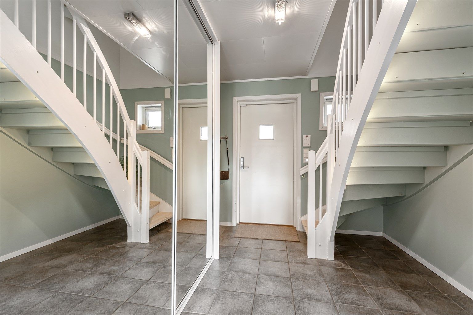 Entréen har flislagt gulv med gulvvarme og en romslig skyvedørsgarderobe med speilfronter for yttertøy og sko.