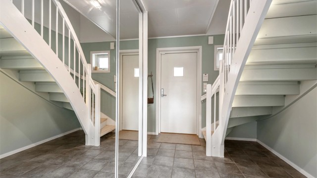 Entréen har flislagt gulv med gulvvarme og en romslig skyvedørsgarderobe med speilfronter for yttertøy og sko.
