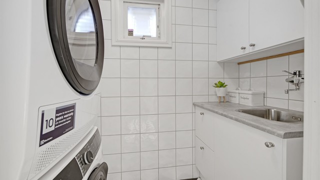 Vaskerom - adkomst fra bad - flislagt gulv og vegger - innredning med servant fra 2019 - varmtvannsbereder fra 2019 - opplegg til vaskemaskin og tørketrommel