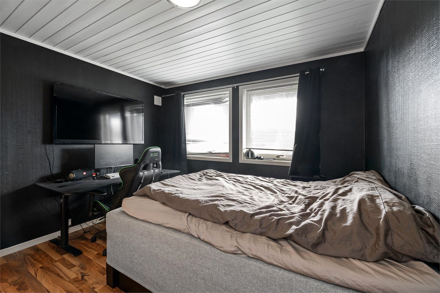 Soverom med malte, tapetserte vegger og laminat på gulvet