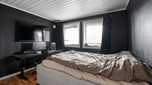 Soverom med malte, tapetserte vegger og laminat på gulvet